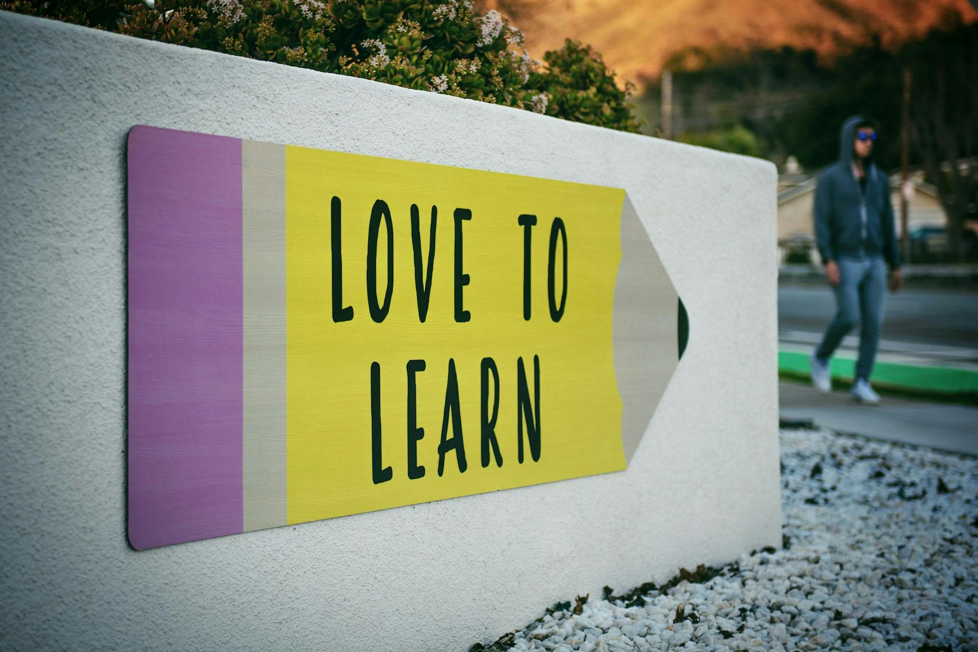 Placa em formato de lápis escrito Love To Learn